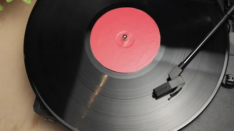 Close-up of a vintage record player spinning a vinyl disc with a red label Stockbeeldmateriaal 340844816