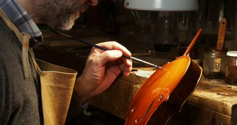 Close up of a violin maker carefully applying varnish on a new handcrafted Video stock 300541116