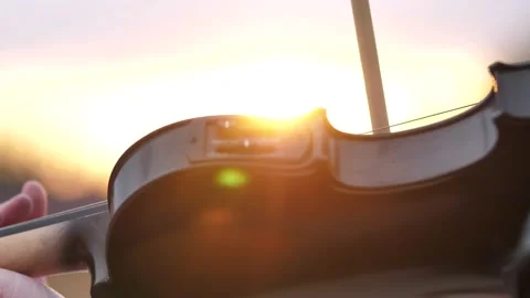 Close-up of a violin player, a violinist performs a solo in a pink sunset in the Stock Footage 198764113