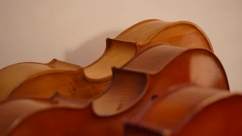 Close up of violins lying side by side on pale background Video stock 347813758