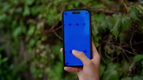 Close-up visual focus on a hand holding a modern smartphone with a blue screen Stock Footage 310351854
