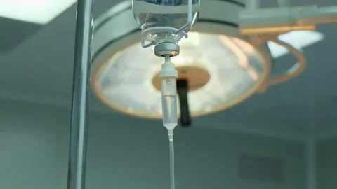 Close-up of vitamin IV drip chamber dripping on medical clinic. Stock Footage 273207135