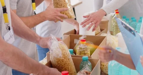 Close Up Of Volunteer Team Hands Packing Food Boxes At Humanitarian Center Stock Footage 285376443