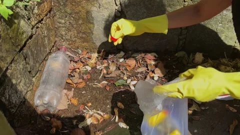 Close-up of a volunteer's hands picking up a plastic bottle and other debri.. Stock Footage 236655442