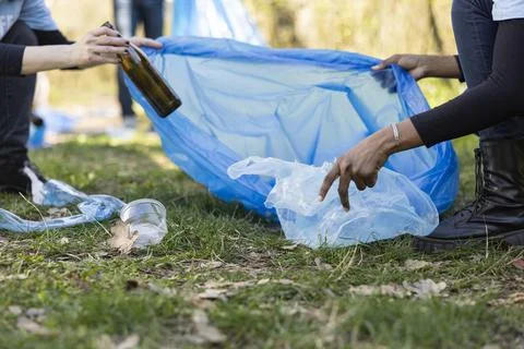 Close up of volunteers using trash bag to gather plastic waste in woodland Stock Photos