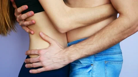 Close-up of the waists of hugging young lovers topless against white background Stock Footage 146652506