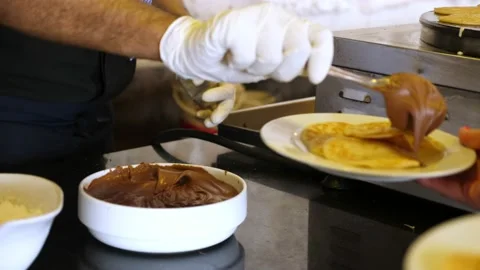 Close-up, a waiter in protective gloves serves chocolate cream to pancakes. new Stock-Footage 136838948