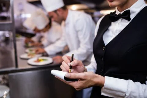 Close-up of waitress with note pad in commercial kitchen Stock Photos