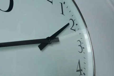 A close-up of a wall clock showing a quarter to two. Stock Photos
