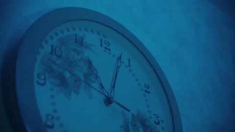 Close-up of wall clock that shows 11 pm in a room under blue light Stock Footage 247800552
