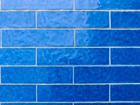 A close-up of a wall featuring various shades of blue rectangular tiles Stock Photos