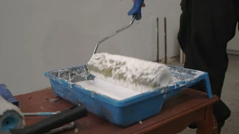 Close-up of a wall paint roller dipped in white paint. Slow motion. Stock Footage 141554050