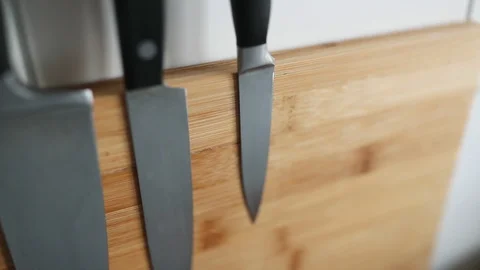Close-up on the wall set of kitchen knives on a wooden magnetic board Stock Footage 129079275