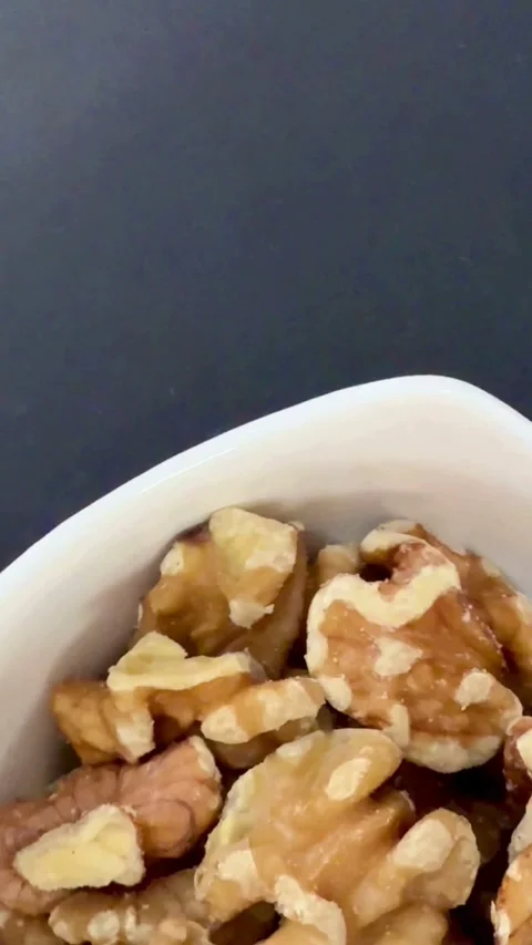 Close up of walnut halves in a white bowl Video stock 334592704