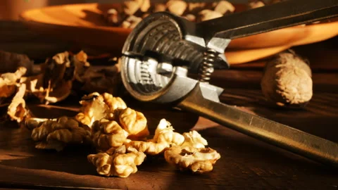 Close-up of a walnut kernel and shell and a metal nutcracker on a wooden table i Video stock 219668184