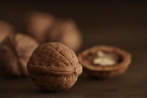 Close-up of walnut kernels and shelled nuts on a wooden table on a dark Stock Photos