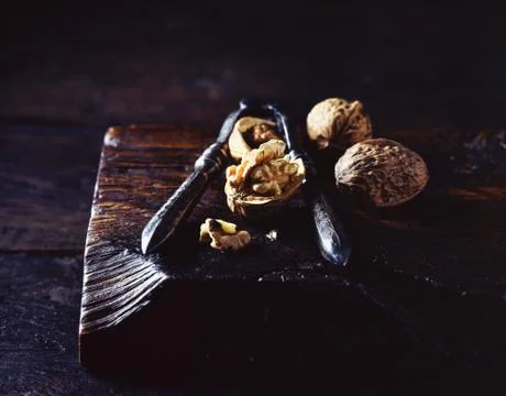 Close up of walnuts and nut cracker on wooden cutting board Stock Photos