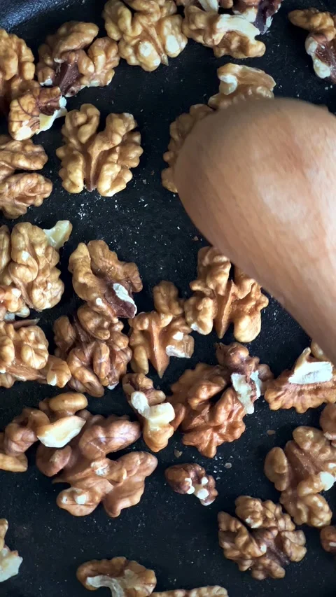 Close up of walnuts being roasted in black spinning pan. Slow motion. Stock Footage 221985276