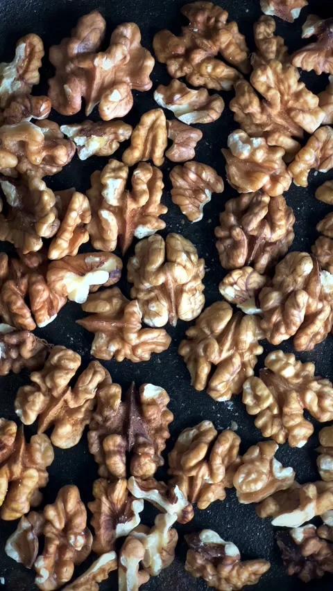 Close up of walnuts being roasted in black spinning pan. Stock Footage 221985315