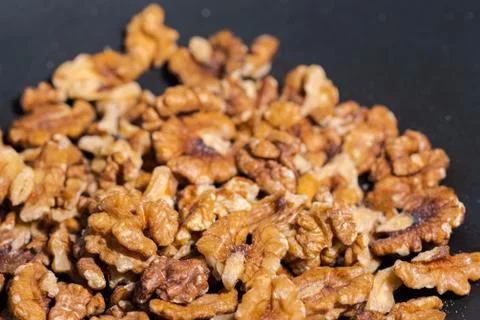 Close up of walnuts in dark grey cast iron pan for roasting spices Stock Photos