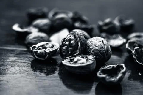 Close up of walnuts in shell and some broken on brown colored wooden surface. Stock Photos
