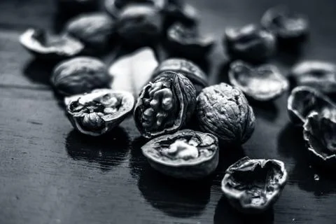 Close up of walnuts in shell and some broken on brown colored wooden surface. Stock Photos
