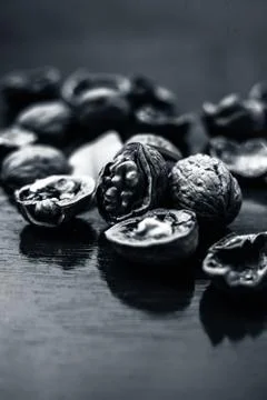 Close up of walnuts in shell and some broken on brown colored wooden surface. Stock Photos