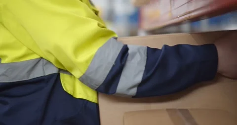 Close up of warehouse worker putting cardboard box on shelf Stock Footage