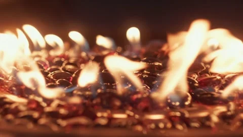 Close-Up of Warm Amber and Orange Flames on Red Fire Glass Rocks Stock Footage 313636618