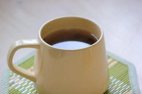 Close up of a warm ceramic mug filled with tea on a green bamboo coaster on.. Foto stock