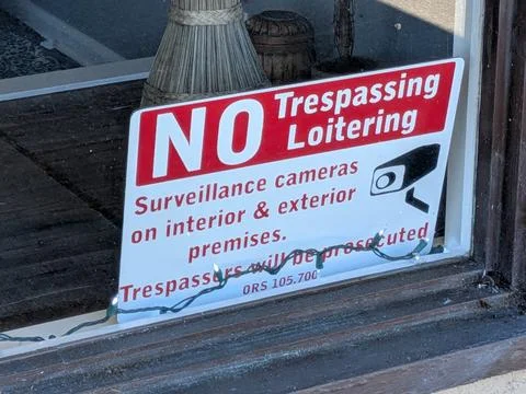 Close-up of a warning sign in a window reading “No trespassing or loitering" Stock Photos