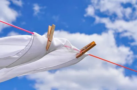 Close up of washed linen hanging on red rope with clothepins outside 写真素材