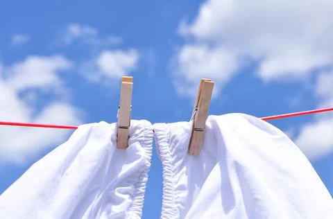 Close up of washed linen hanging on red rope with clothepins outside Stock Photos