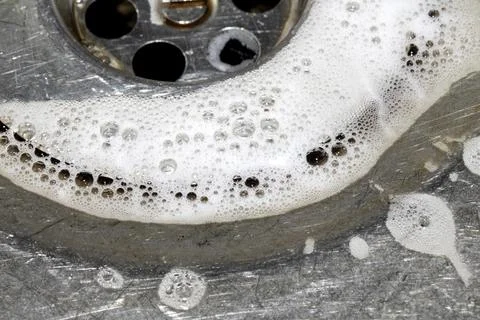 Close up of washing up liquid bubbles flowing down the kitchen sink Stock-Fotos
