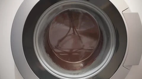 Close-up of a washing machine spinning clothes during a wash cycle. Video stock 308794285