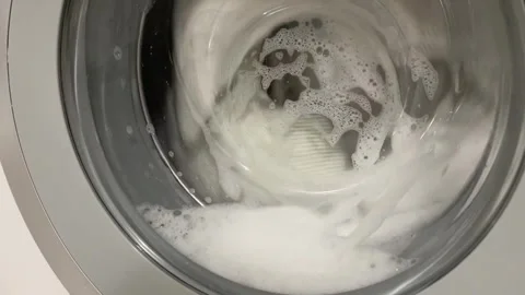 Close-up of a washing machine washing light-colored bed linen Stock Footage 314834416