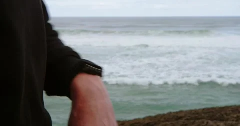 A close-up of a watch on one hand in a rocky coastal setting. Stock Footage 333208318