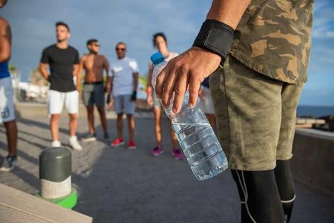 Close-up on the water bottle held by a man during an outdoor work out with .. Stock Photos