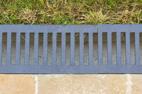 Close-up of water drain gutter that separates the lawn from the paved terrace Stock Photos