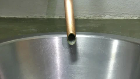 Close up on water dripping slowly from a copper pipe in to sainless steel Stock Footage 312672842