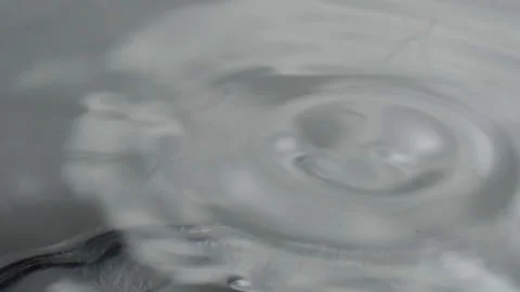 Close Up Water Drop Creating Circular Ripple Pattern on Calm Water Surface Stock Footage 346797012