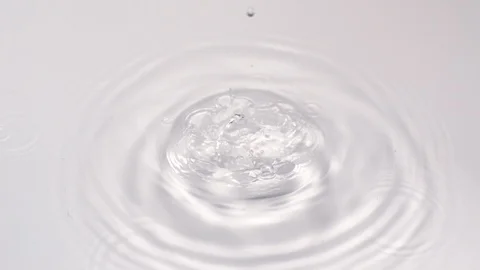 Close up of a water drop making ripples in white background, slow motion Stock Footage 93362452