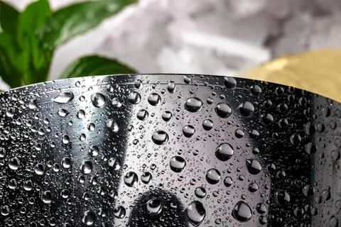 Close-up of water droplets on black surface with blurred background Stock Photos