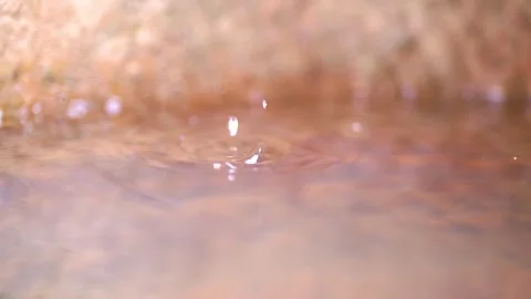 Close up of water droplets falling into a calm pool creating circular ripples Stock Footage 341999852