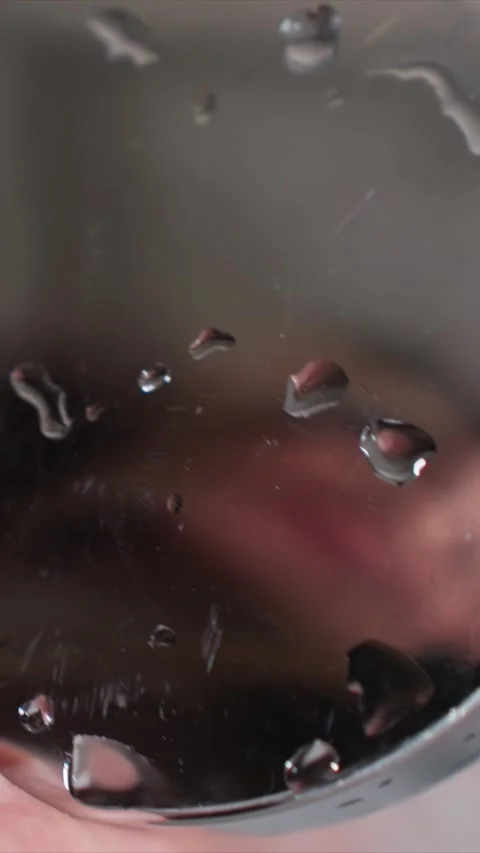 Close up water droplets on reflective surface with soft lighting and hand Stock Footage 346791755