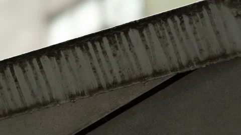 Close up of water droplets sliding down a metal ledge and dripping into the air Stock Footage 328378093