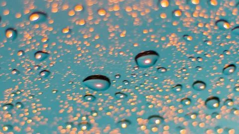 Close up of water droplets on a textured surface with warm light reflections Stock Photos