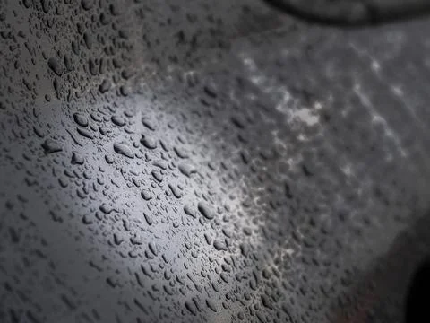 Close up of water drops on dark gray car after rain. Stock Photos