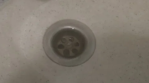Close up of water drops falling into a dirty domestic sink drain. The dripping Stock Footage 343963911