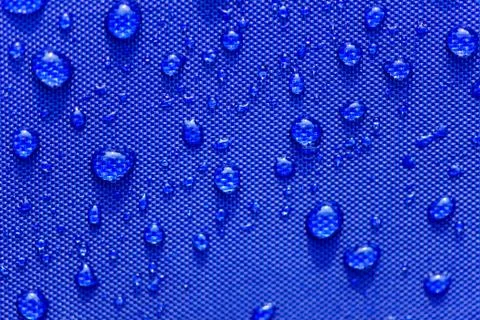 Close up Water drops pattern over a blue waterproof cloth background. World W Stock Photos